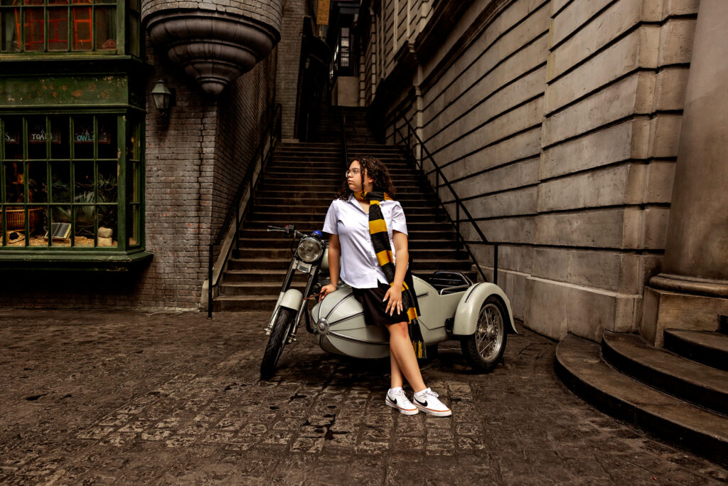 Haleigh sitting on Hagrid's motorbike with sidecar in the streets of Diagon Alley at Universal Orlando during her magical senior photo