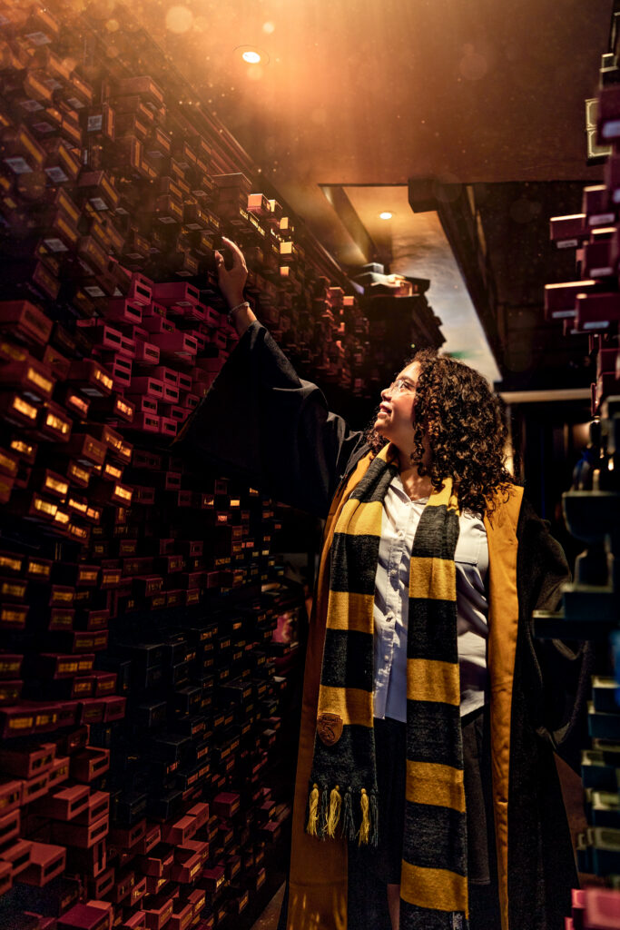 Haleigh reaching for a wand in the magical shelves of Ollivanders at Universal Orlando, captured during her senior session with cinematic lighting